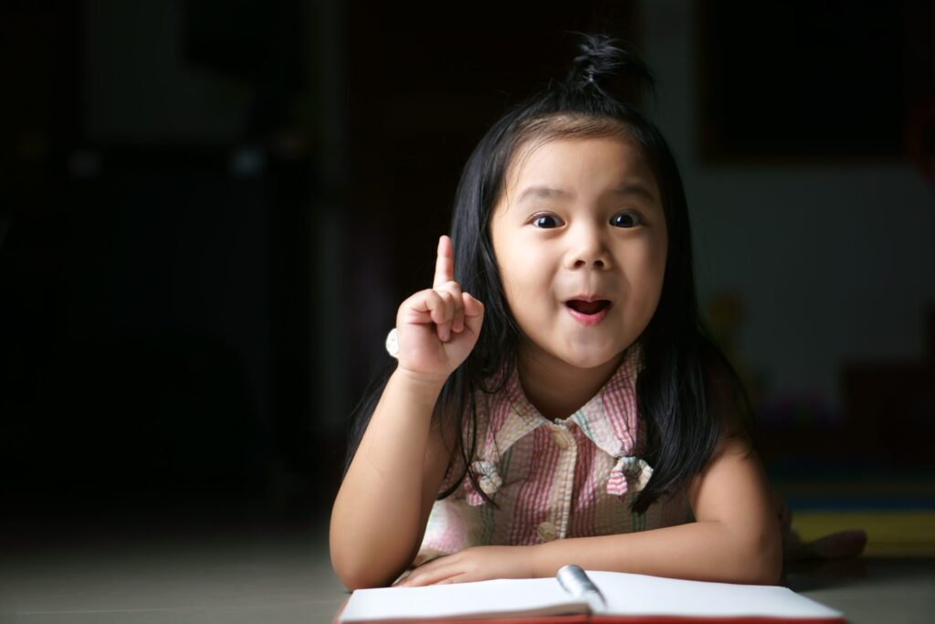 girl pointing up while reading a book