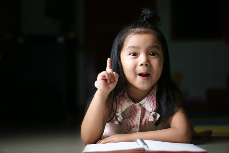 girl pointing up while reading a book